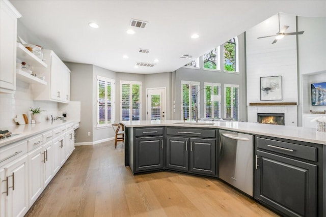 kitchen with visible vents, dishwasher, a sink, light wood finished floors, and white cabinetry