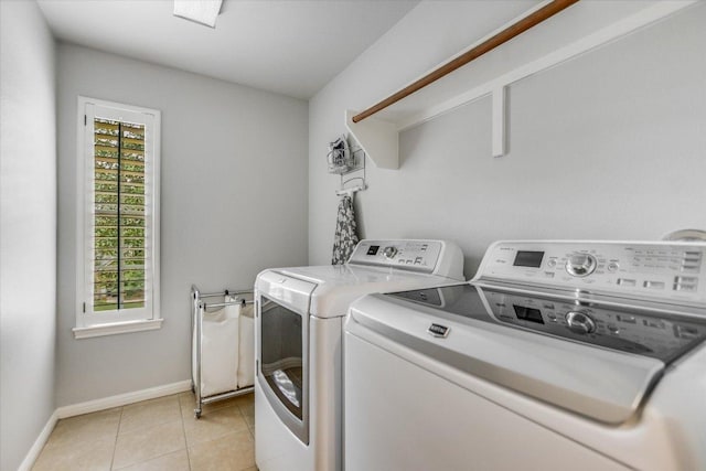 laundry room featuring light tile patterned flooring, laundry area, washing machine and dryer, and baseboards