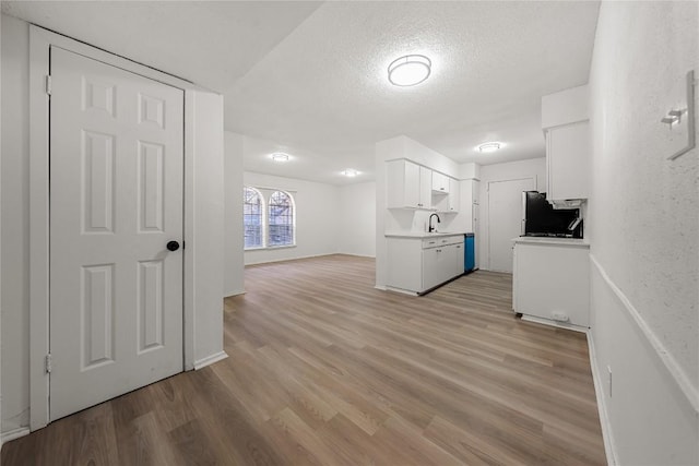 101 E 33rd St Unit 104, Austin, TX 78705 - kitchen featuring light wood-style floors, light countertops, a textured ceiling, white cabinetry, and a sink