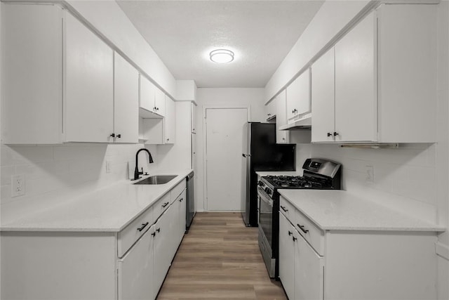 101 E 33rd St Unit 104, Austin, TX 78705 - kitchen with white cabinets, appliances with stainless steel finishes, a sink, light wood-style floors, and backsplash