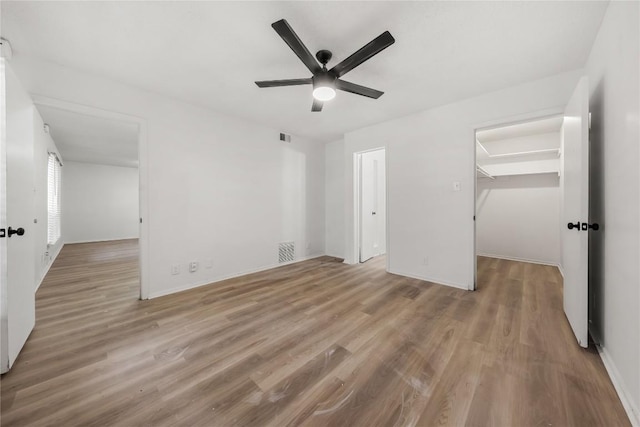 101 E 33rd St Unit 104, Austin, TX 78705 - unfurnished bedroom featuring a closet, wood finished floors, baseboards, a walk in closet, and a ceiling fan