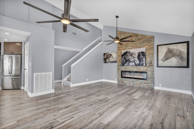 721 Fawn, Horseshoe Bay, TX 78657 - unfurnished living room with a ceiling fan, wood finished floors, high vaulted ceiling, stairway, and a fireplace