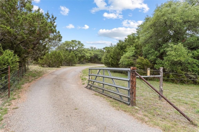 view of road with a gate, a gated entry, and a view of trees
