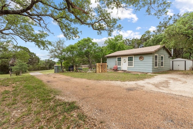 exterior space featuring an outbuilding, a shed, driveway, and fence