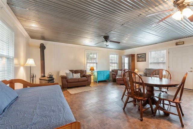 tiled dining area featuring ornamental molding, a wood stove, and a ceiling fan