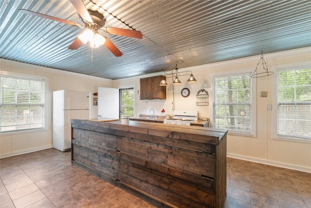 kitchen with dark tile patterned floors, ceiling fan, a kitchen island, a sink, and white appliances