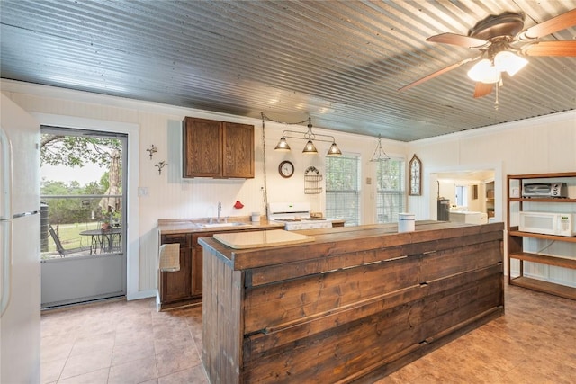 kitchen featuring a ceiling fan, white appliances, a center island, a sink, and light tile patterned floors