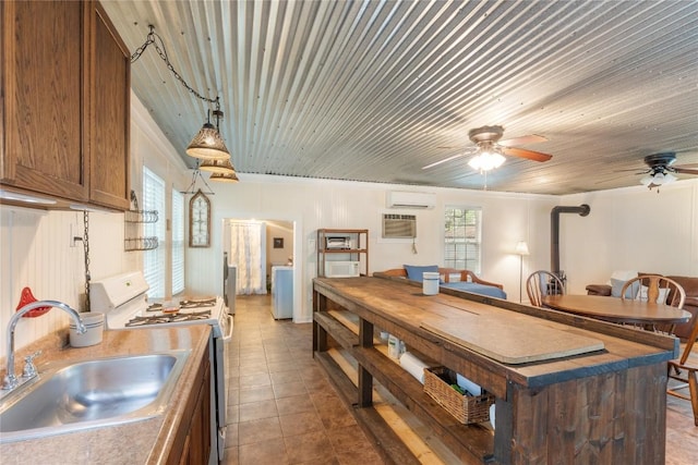 kitchen with ceiling fan, a sink, an AC wall unit, a healthy amount of sunlight, and white range with gas cooktop