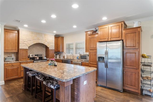 kitchen with crown molding, appliances with stainless steel finishes, a sink, and visible vents