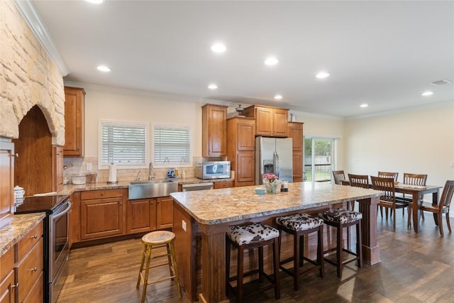 kitchen with crown molding, a breakfast bar, a sink, appliances with stainless steel finishes, and backsplash
