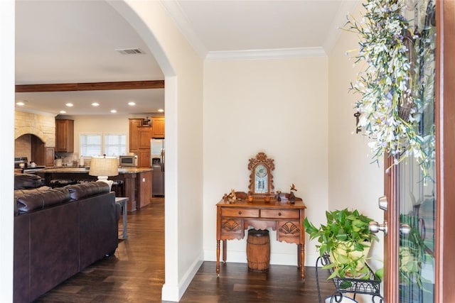 foyer entrance featuring dark wood-type flooring, arched walkways, visible vents, and ornamental molding