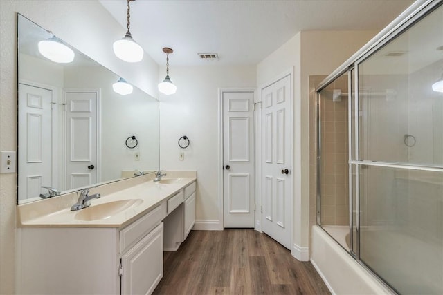 13109 Marble Falls Cv, Austin, TX 78729 - bathroom with double vanity, wood finished floors, and combined bath / shower with glass door