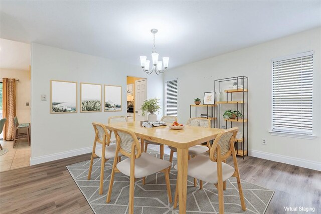 dining area featuring baseboards, wood finished floors, and a notable chandelier