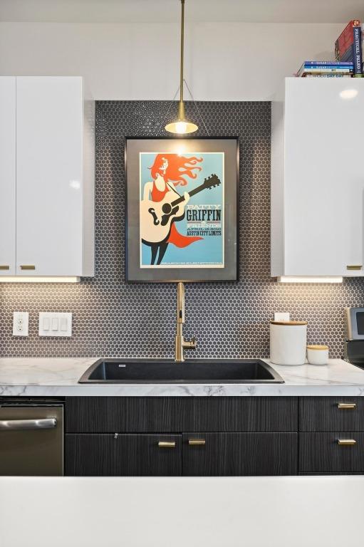 kitchen with a sink, light countertops, decorative backsplash, and stainless steel dishwasher