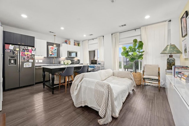 living area with recessed lighting, visible vents, and dark wood-style floors