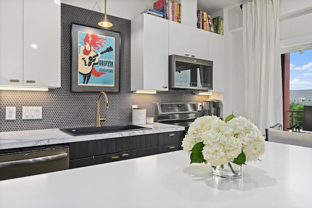 kitchen featuring a sink, appliances with stainless steel finishes, backsplash, and white cabinetry