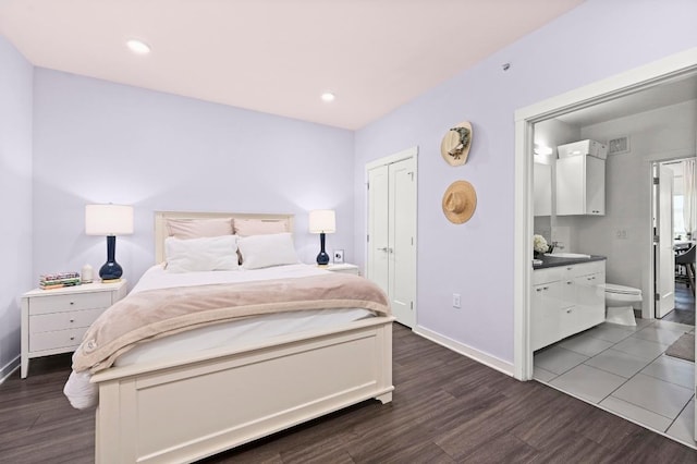 bedroom with visible vents, baseboards, ensuite bathroom, a sink, and dark wood finished floors