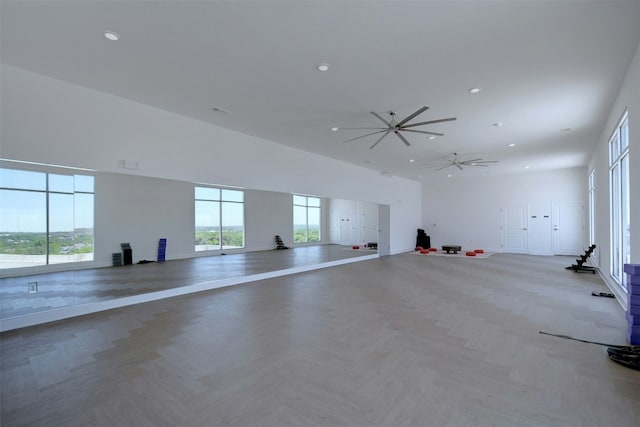 empty room with baseboards, recessed lighting, plenty of natural light, and a high ceiling