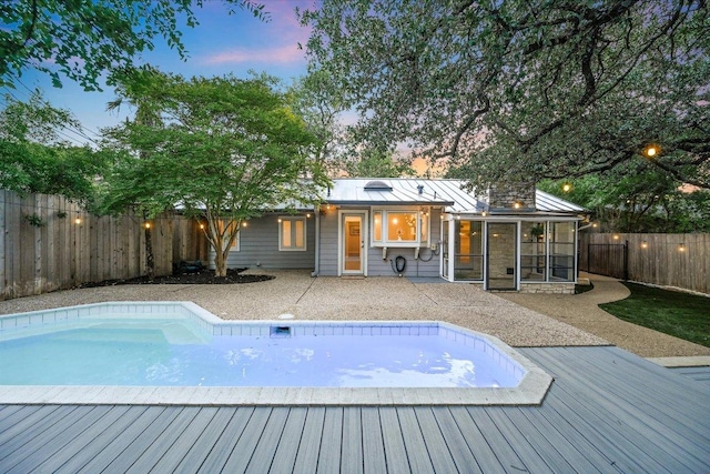 3514 Lakeland Dr, Austin, TX 78731 - pool at dusk with a wooden deck, a sunroom, and a fenced backyard