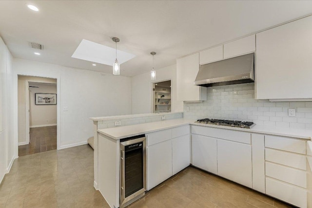 3514 Lakeland Dr, Austin, TX 78731 - kitchen with beverage cooler, wall chimney exhaust hood, stainless steel gas cooktop, decorative backsplash, and a skylight