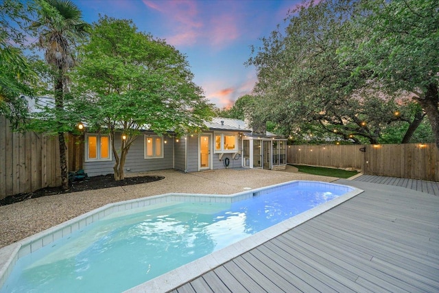3514 Lakeland Dr, Austin, TX 78731 - pool at dusk featuring a fenced backyard, a sunroom, a deck, and a fenced in pool