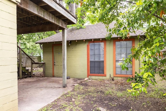 exterior space with fence, a shingled roof, and a patio area