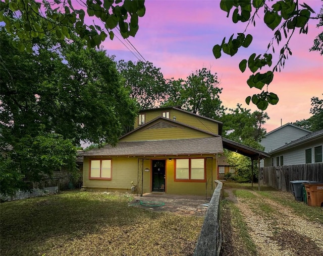 bungalow-style house with dirt driveway and fence