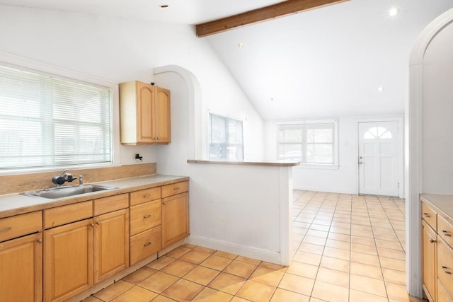 kitchen featuring vaulted ceiling with beams, a sink, light tile patterned floors, and light countertops