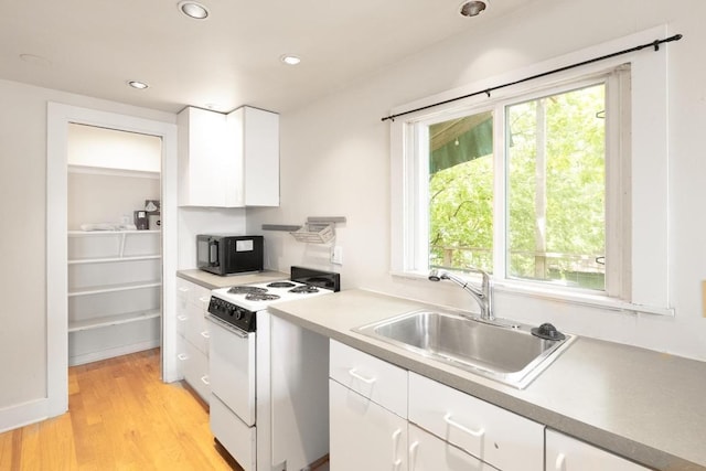kitchen featuring black microwave, white electric range, a sink, white cabinets, and recessed lighting