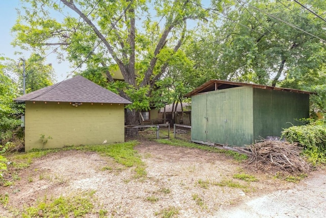 view of yard with fence, a gate, an outdoor structure, and a storage unit