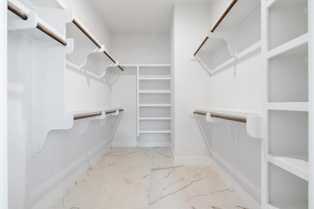 walk in closet featuring marble finish floor