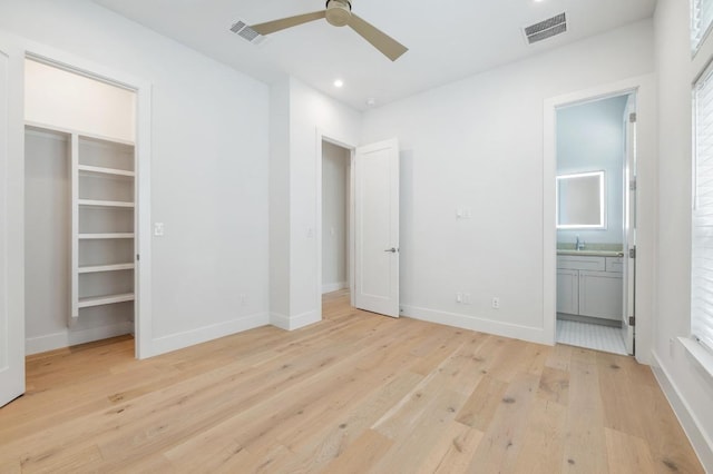 unfurnished bedroom with ensuite bath, baseboards, visible vents, and light wood-type flooring