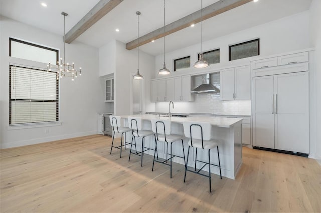 13312 Galleria Cir, Austin, TX 78738 - kitchen with wall chimney range hood, a breakfast bar area, tasteful backsplash, light countertops, and an island with sink