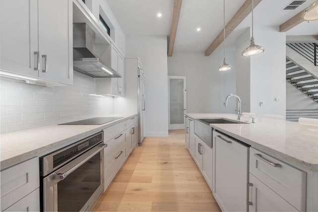 kitchen with beam ceiling, a sink, black electric stovetop, stainless steel oven, and wall chimney exhaust hood
