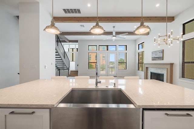 kitchen with pendant lighting, a fireplace, open floor plan, a sink, and ceiling fan with notable chandelier