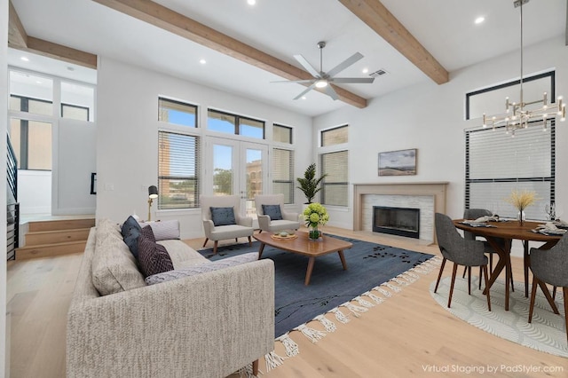13312 Galleria Cir, Austin, TX 78738 - living room featuring beamed ceiling, a glass covered fireplace, a chandelier, wood finished floors, and ceiling fan