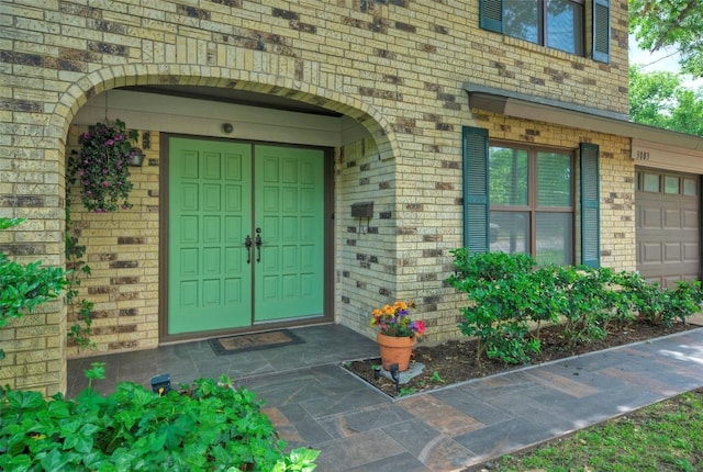 property entrance with brick siding and a garage