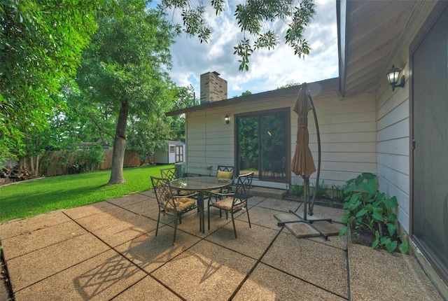view of patio with fence, an outbuilding, outdoor dining area, and a shed