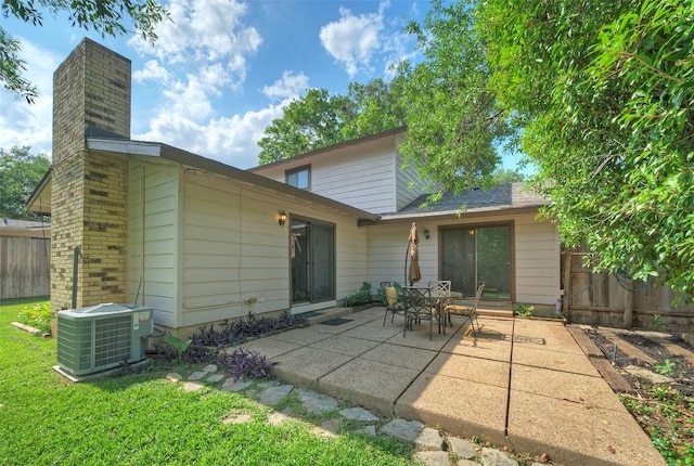 rear view of house featuring central air condition unit, fence, a chimney, and a patio area