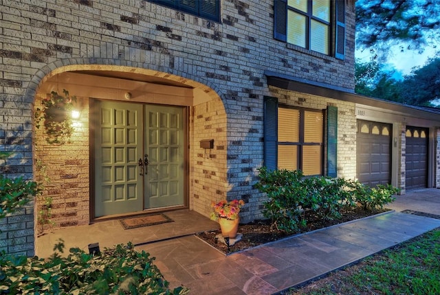 doorway to property featuring brick siding and a garage