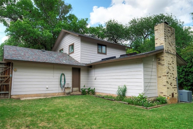view of front of home featuring a chimney, cooling unit, and a front yard