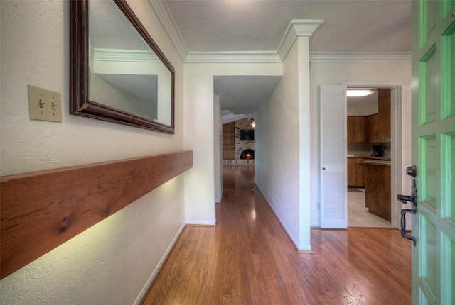 hallway with crown molding, baseboards, and wood finished floors