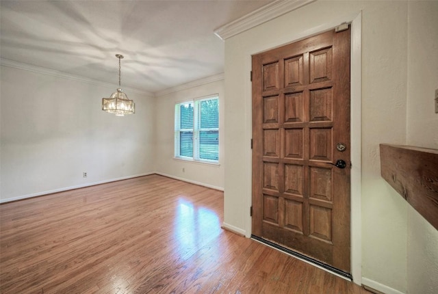 entryway featuring baseboards, ornamental molding, wood finished floors, and a chandelier