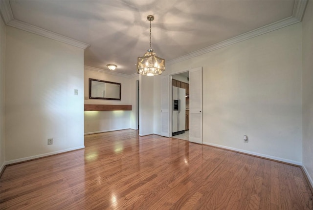 interior space featuring crown molding, baseboards, a chandelier, and wood finished floors