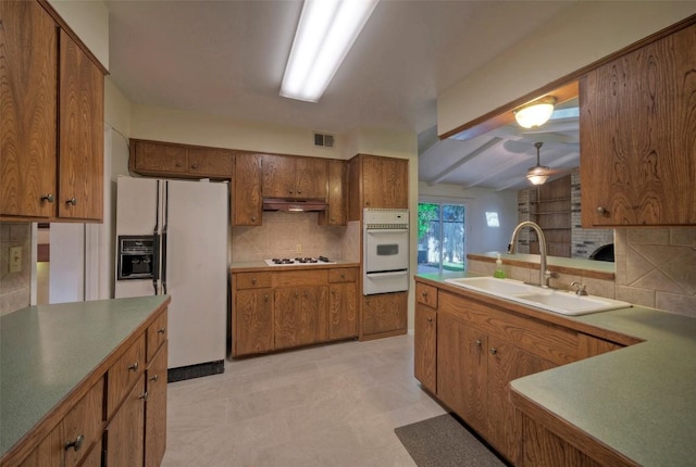 kitchen with brown cabinetry, visible vents, tasteful backsplash, a sink, and white appliances