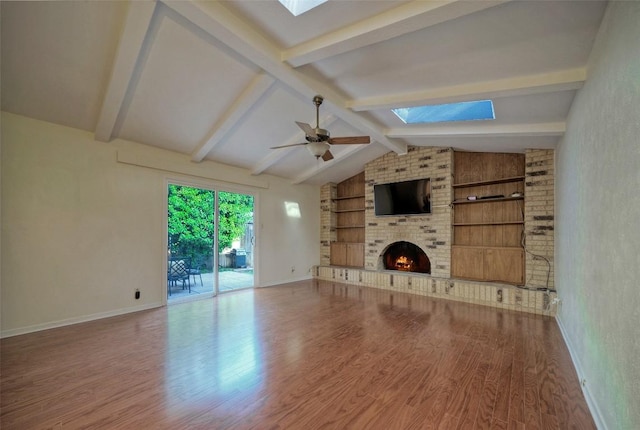 unfurnished living room with a brick fireplace, wood finished floors, baseboards, vaulted ceiling with skylight, and built in shelves