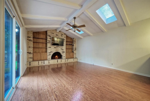 unfurnished living room with vaulted ceiling with skylight, a fireplace, built in shelves, baseboards, and wood finished floors