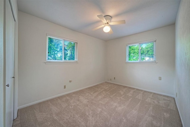 empty room featuring baseboards, ceiling fan, and light carpet