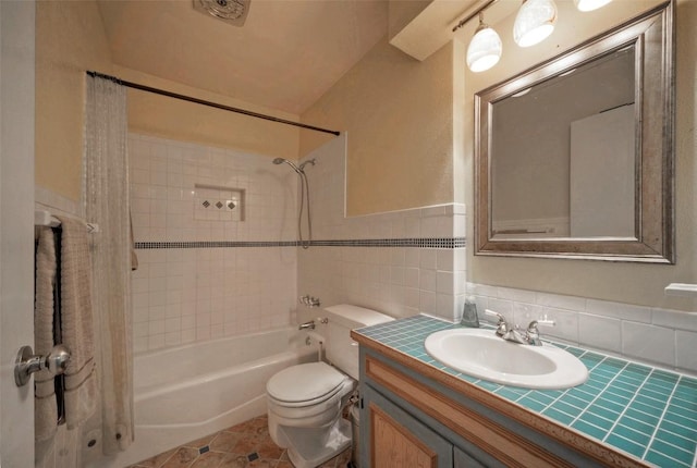 bathroom featuring vanity, shower / tub combo with curtain, toilet, tile walls, and a wainscoted wall