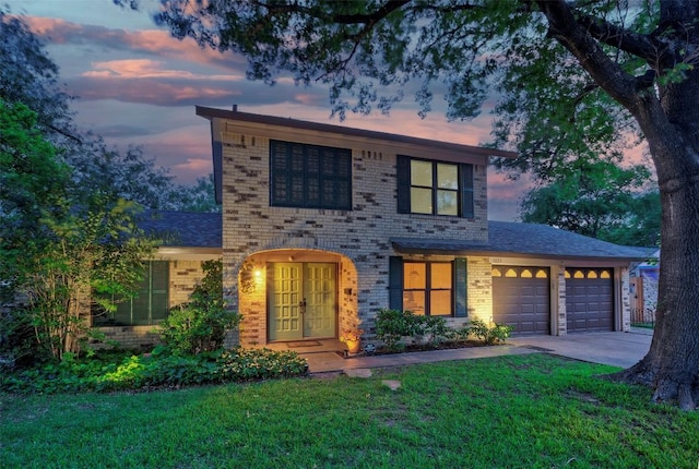 view of front of home with brick siding, a garage, a front yard, and concrete driveway